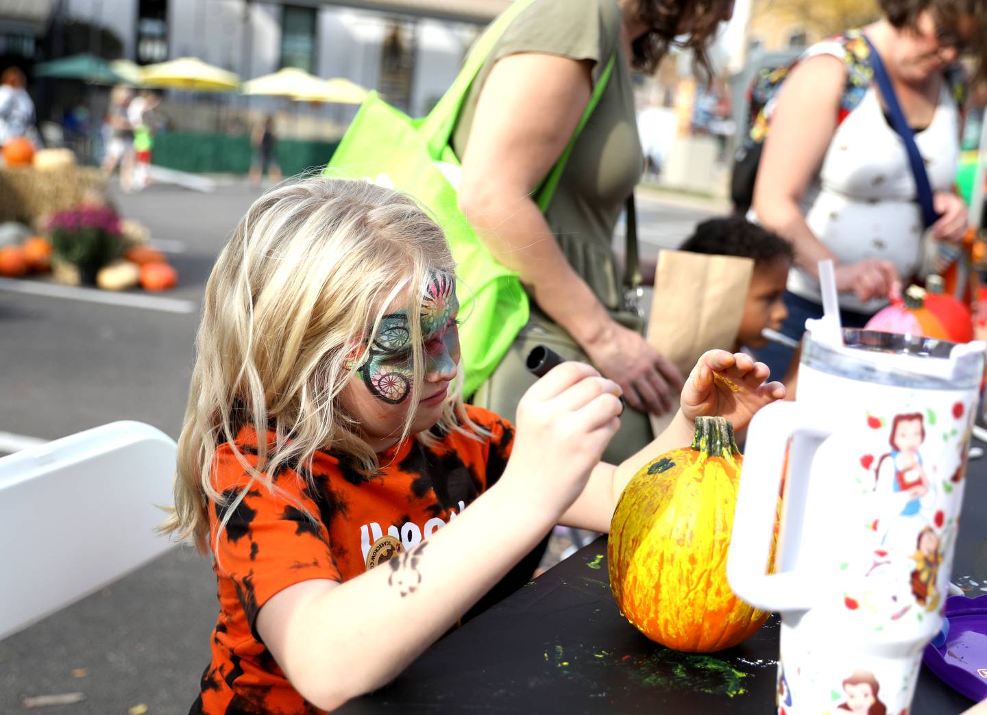 Lilly Schild, 7, of St. Charles paints a pumpkin in the activity zone along Riverside Avenue on Friday, Oct. 11, 2024 during Scarecrow Weekend in downtown St. Charles.