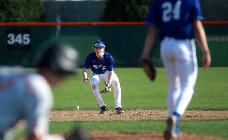 Wheaton North's Alex Popham scoops up a ground ball during a game against St. Charles East on Wednesday, April 23, 2025 in St. Charles.