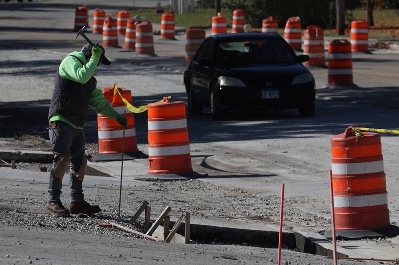 A car drives along East Washington Street as a construction worker does work in Joliet.