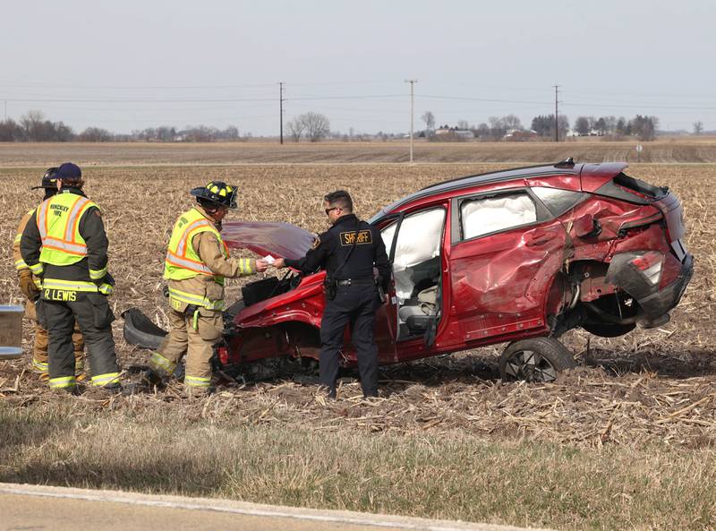 Hinckley firefighters and a DeKalb County sheriff’s deputy check on a badly damaged vehicle in a cornfield on the east side of Somonauk Road south of McGirr Road Wednesday, March 25, 2026, after a two vehicle crash near Hinckley.