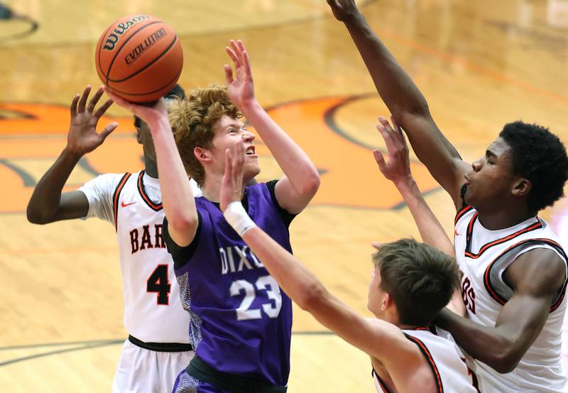 Dixon’s Austin Hicks shoots between three DeKalb defenders during their game Tuesday, Dec. 12, 2023, at DeKalb High School.