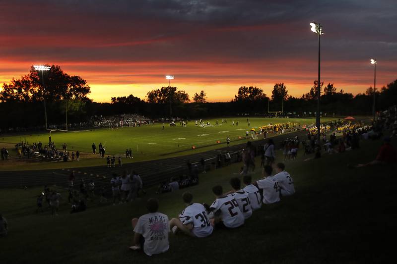 Prairie Ridge junior varsity players watch the Prairie Ridge Jacobs football game as the sun sets during a Fox Valley Conference football game on Friday, Aug 30, 2024, at Jacobs High School in Algonquin. The sunset of the early season football games show of natures glory in one of my favorite photos of the football season.