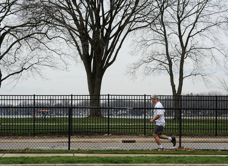 A man runs along Lake Shore Drive near Main Beach in Crystal Lake on April 13, 2022. The city has been working to make Crystal Lake more sustainable, environmentally friendly, and walkable.