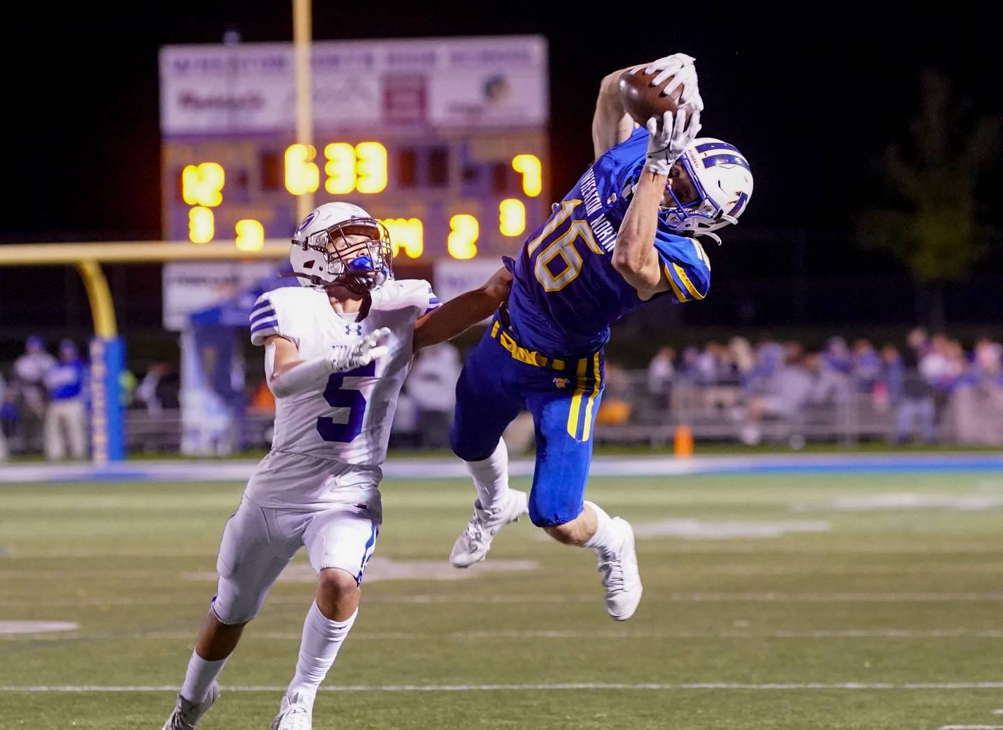 Wheaton North's Matt Kuczaj (16) makes a diving catch against Geneva’s Dylan Reyes (5) during a football game at Wheaton North High School on Friday, Oct. 6, 2023.