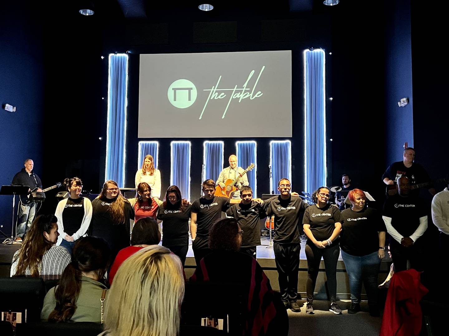 Teens and young adults participate in a meeting of The Center, a nonprofit organization that ministers to youth, at The Table in Joliet. A praise band plays in the background.