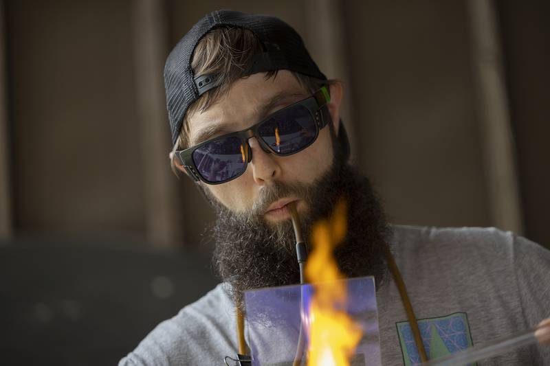 Joseph Wallander concentrates on a glass piece Friday, June 27, 2025, during Herbal Root’s CannaFest. The fest had several glass blowers making and selling their pieces.