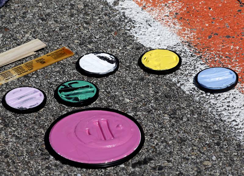Paint can lids show off the colors used in painting a parking students parking spot at Marian Central Catholic High School on Tuesday, Aug. 13, 2024.