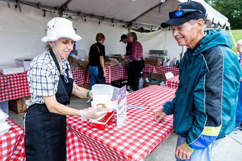 Slovenian Grape Harvest Festival volunteer Mary-Fran Smaron serves Joliet resident Jack Mastalesh a potica at the Rivals Park Picnic Grounds on Sept. 29, 2024.