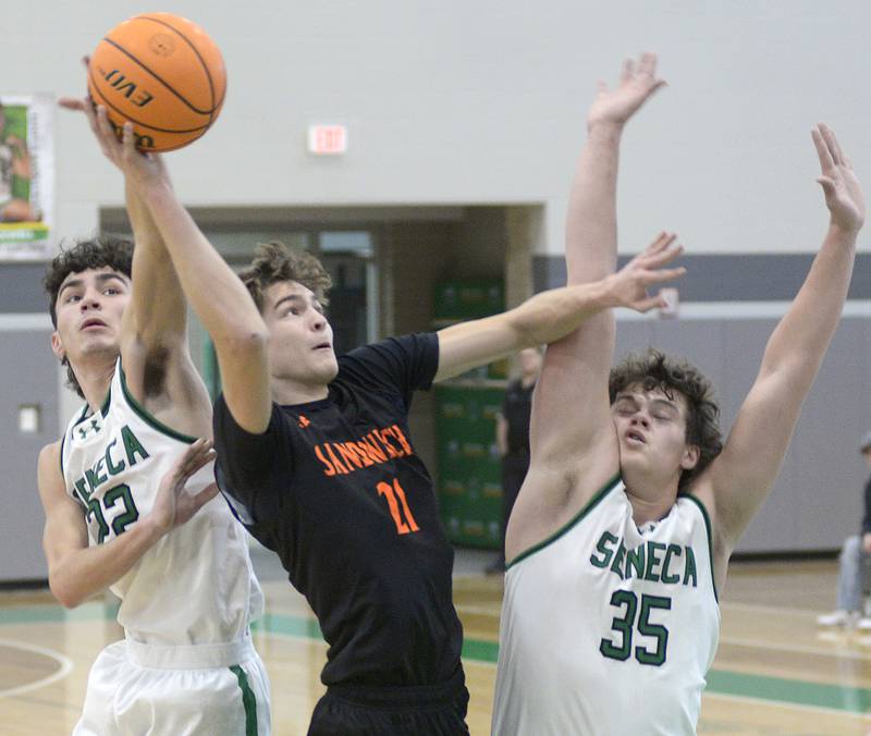 Sandwich’s EJ Treptow shoot over the blocks by Seneca’s James Zydron and Zeb Maxwell  in the 1st period Saturday during the MLK Shootout at Seneca.