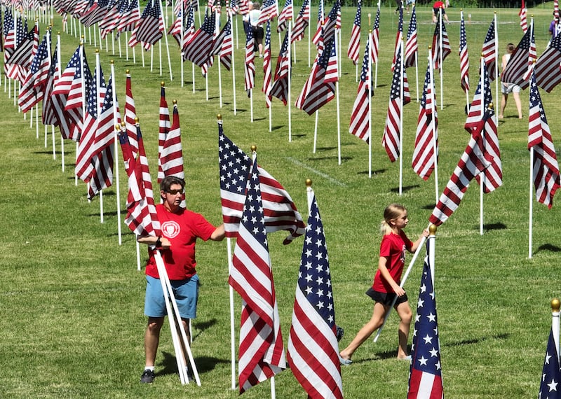 Andy Pupius of West Chicago and his daughter, Lili, 9, help place flags during setup for the Wheaton Field of Honor at Seven Gables Park on Saturday, June 28, 2025.