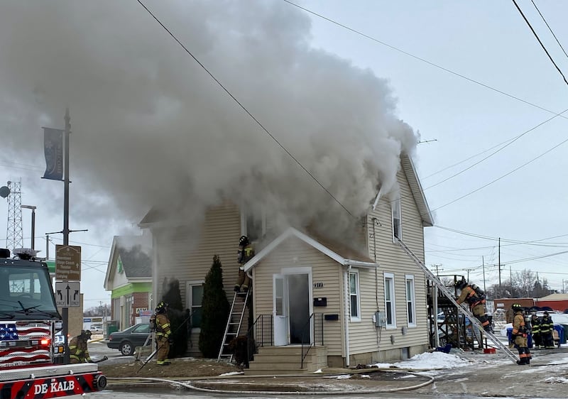 A firefighter on a ladder works to break the upstairs window to a two-story duplex to get water into the structure on Saturday, Jan. 24, 2026, at Seventh Street and East Lincoln Highway in downtown DeKalb. Fire Chief Luke Howieson said the rampant flames spread too quickly into the walls for it to be safe for firefighters to remain in the building.