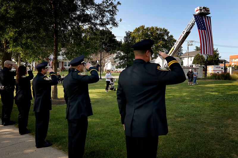 Firefighters salute as the flag is raised during a 9/11 remembrance ceremony on Sept. 11, 2024, at Veterans Park in McHenry.