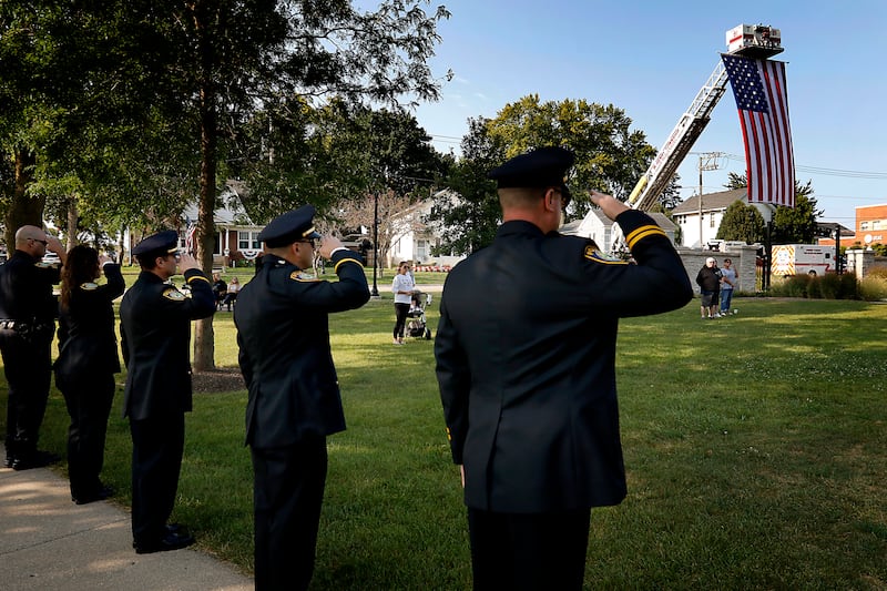 Firefighters salute as the flag is raised during a 9/11 remembrance ceremony on Sept. 11, 2024, at Veterans Park in McHenry.