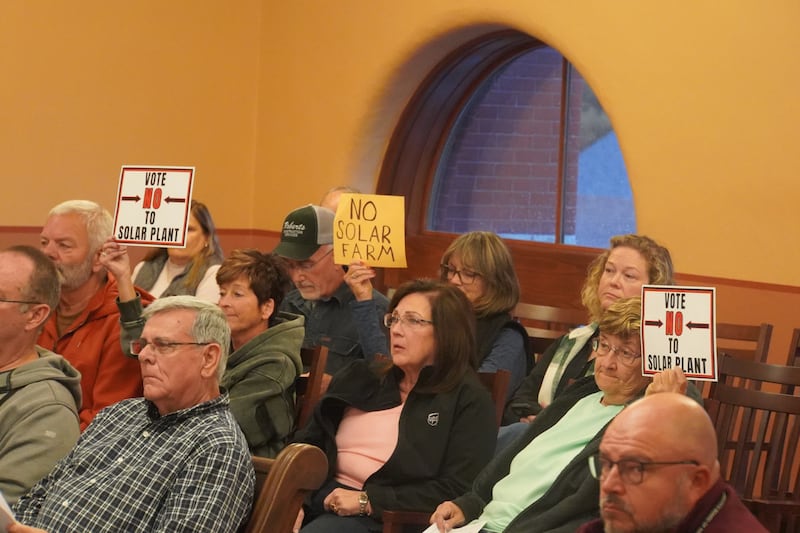 Ogle County residents hold up signs against solar panels at the Ogle County Board meeting on Tuesday, Oct. 21, 2025 at the historic Ogle County Courthouse in Oregon.