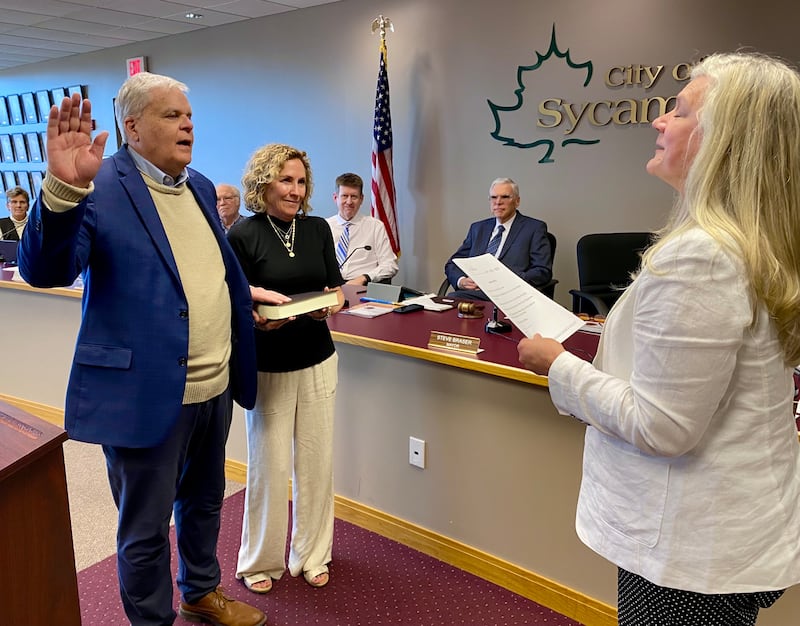 Sycamore Mayor Steve Braser (left) takes the oath of office as his wife, Beth Braser, hold the Bible while City Clerk Mary Kalk (right) swears him in to begin his second term in office on Monday, May 5, 2025, at the Sycamore City Center.