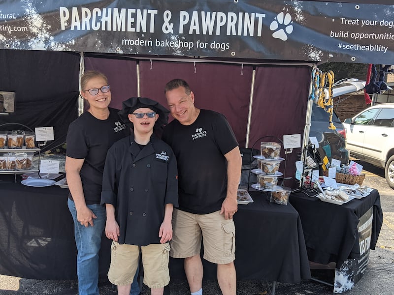 Oswego resident Zachary Pietrowiak, center, bakes wholesome dog treats for his family business, Parchment & Pawprint, which sells its products at the Oswego Country Market. At left is his mother, Christine Pietrowiak, co-founder of the business, and at right is his father, Russell Pietrowiak.