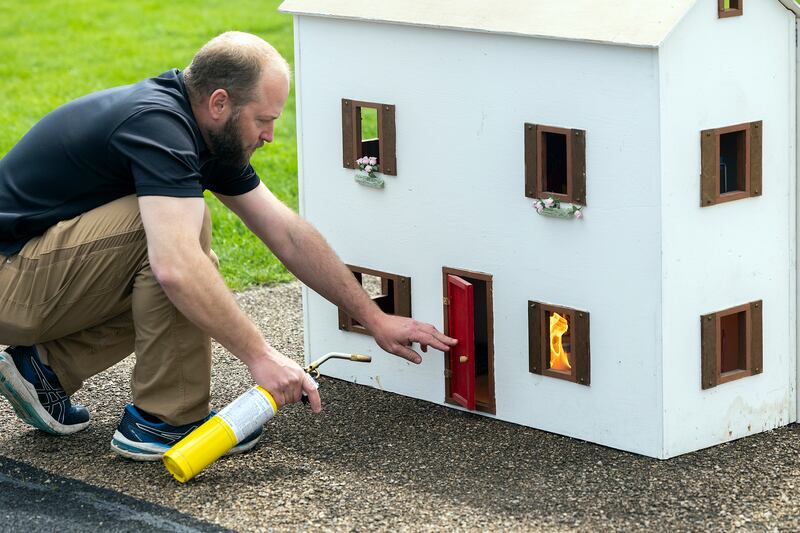 Dixon science teacher Ryan Deets lights up one of the model homes Tuesday, April 22, 2025, outside of DHS. Deets is teaching arson investigation in the school’s forensics science class.