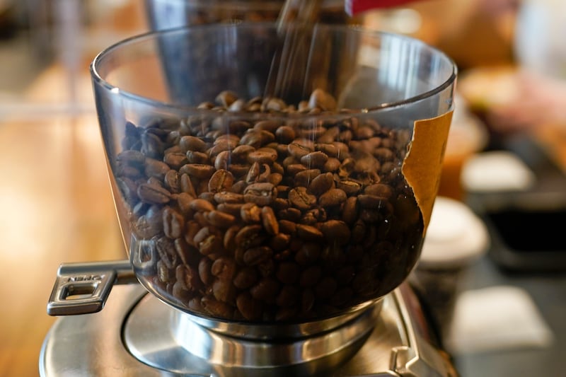 Coffee beans are poured into a grinder at a café.