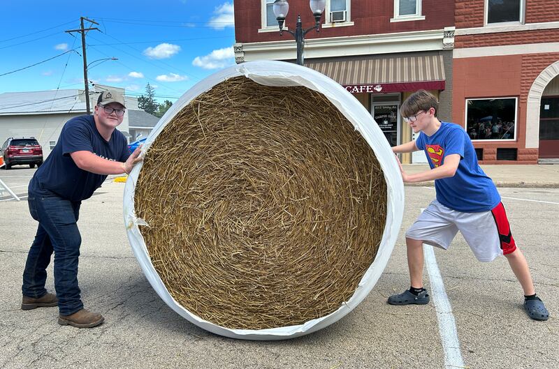 Sawyer Marceau of Polo (left) and Zakkary West of Mt. Morris pose with the large round straw bale they pushed down Wesley Avenue and across the finish line first during the Straw Bale Race at Strawfest on Saturday, Aug. 23, 2025. The 17-year-olds won the event with the fastest time of 9.36 seconds.