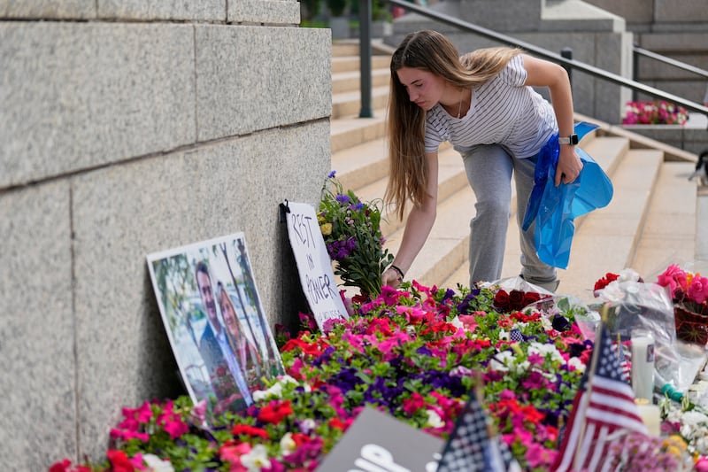 Claire Stein places flowers at a makeshift memorial for Minnesota state Rep. Melissa Hortman and her husband Mark at the state Capitol, Sunday, June 15, 2025, in St. Paul, Minn. (AP Photo/George Walker IV)