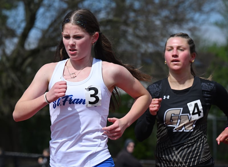 Abby Yarusso of St. Francis has overtaken Lucy Roscoe of Grayslake North on her way to winning the 3,200-meter run during the Schaumburg girls track and field invite on Saturday, April 18, 2026.