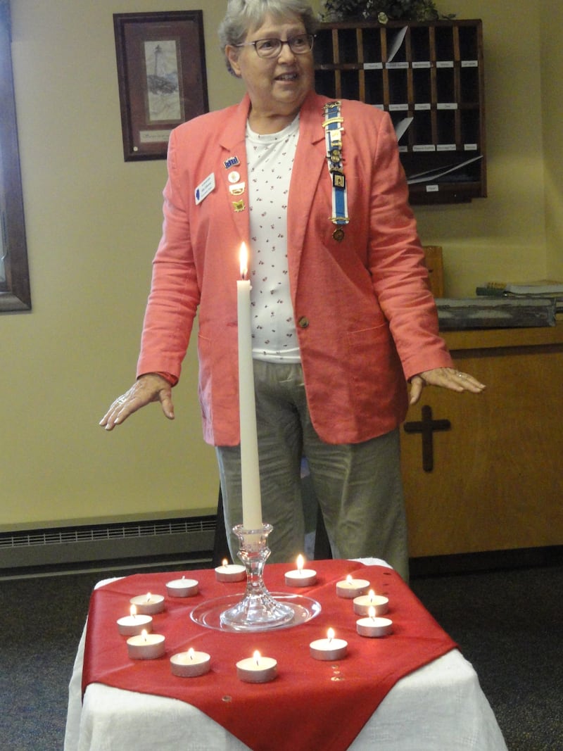 Alice Giberson lights a candle for her patriot, John Harbaugh, during the memorial service.