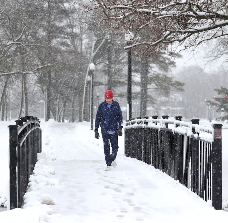 Baraa Saad, 17, from DeKalb, walks across a bridge Tuesday, Jan. 9, 2024, near the Lagoon at Northern Illinois University in DeKalb. Several inches of heavy, wet snow Tuesday was a headache for some and fun for others.