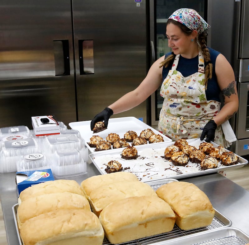 Sara Bartyzel moves coconut macrons to a display tray on Friday, June 27, 2025, at the recently opened Black Market Bakery in downtown Crystal Lake.