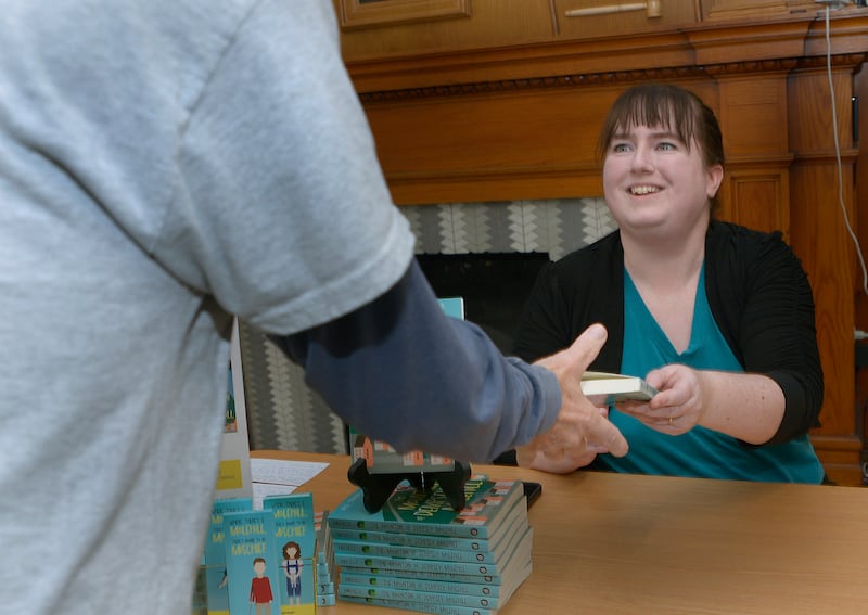 Author Julie Barichello, after signing her new book “The Mountain of Dempsey Molehill,” hands it to a reader Saturday at the Streator Public Library. A book launch party took place where Barichello talked about her new book and answered questions.