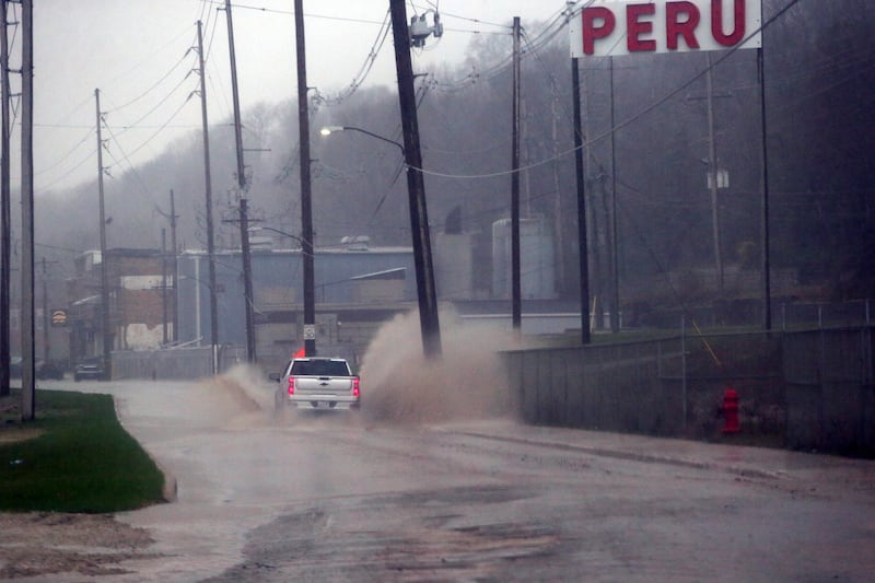 A pickup truck drives through a large puddle of free standing water on Water Street on Wednesday, April 13, 2022 in Peru. Heavy rains drenched the Illinois Valley causing some free standing water on several streets. According to the National Weather Service, the Illinois River is forecasted to rise to 21.5 feet at La Salle before Saturday evening.
