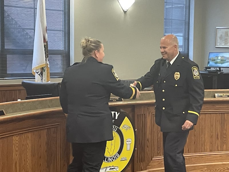 Peru Police Chief Sarah Raymond (left) congratulates Bill Sommer after elevating him to sergeant. At 56, Sommer ascends rank as the oldest patrol officer at the Peru Police Department.