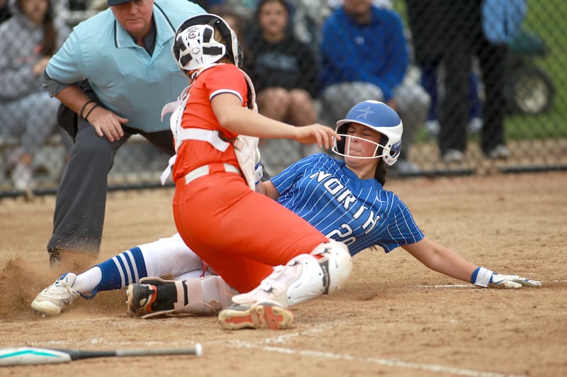St. Charles North's Julianna Kouba slides safely into home plate under the glove of St. Charles East's Hayden Sujack during a game on Friday, April 25, 2025 at St. Charles North.