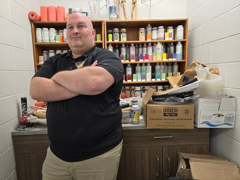 Putnam County art teacher Joshua Curry poses in front of art supplies in his classroom.