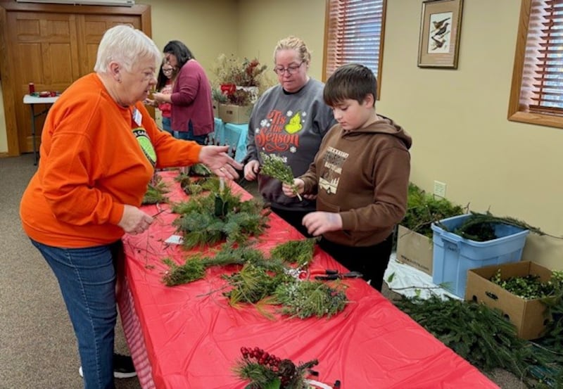 Master Gardener, Barb Dalbach, helps 4-H’er Joey Vinyard create his centerpiece.