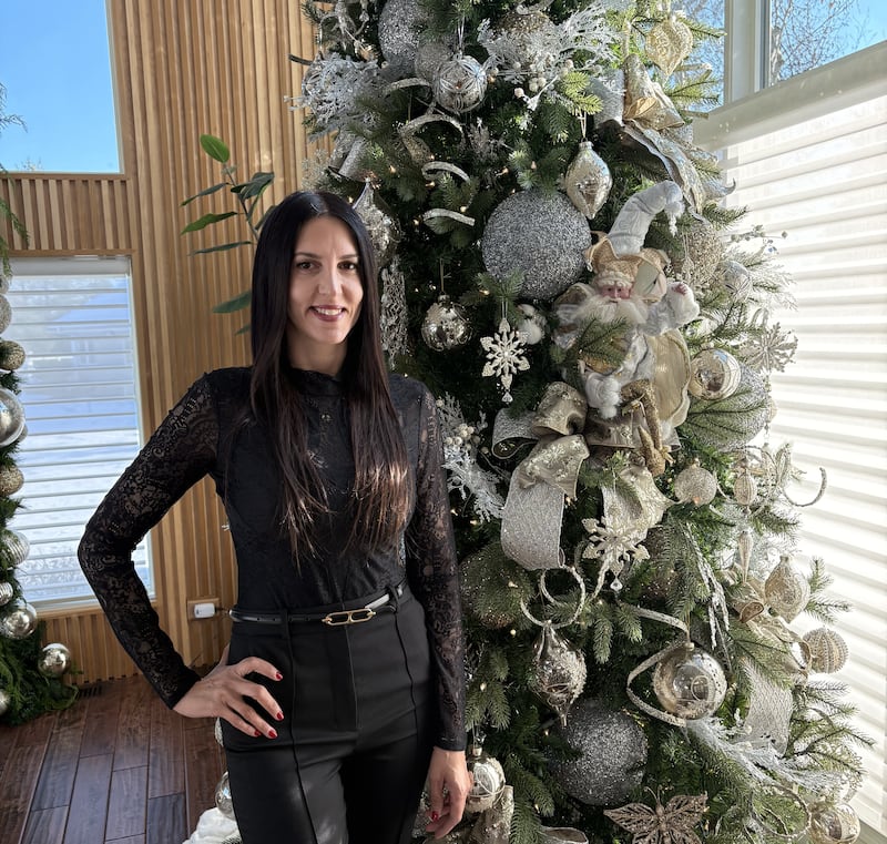 Michelle DeMarco of Geneva beside a Christmas tree she decorated for a client, through her company, DeMarco Designs by Michelle.