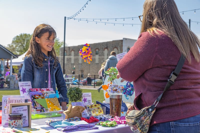 Thaila Scheick speaks with a customer at her table for her store Star Designs at Lemonade day on May 3, 2025 in Utica, Illinois.