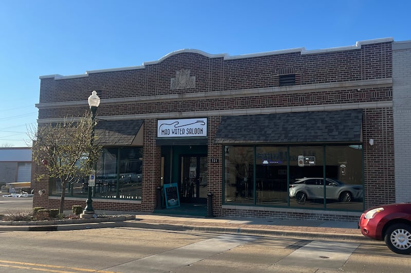 A brick building viewed from the street with a white sign reading "Mad Water Saloon."
