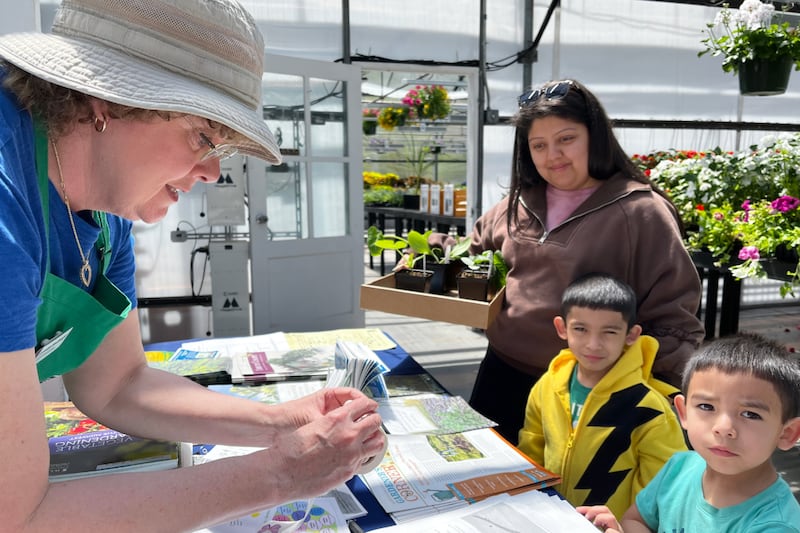 Master Gardener gives resources to children at a Lake County plant sale.