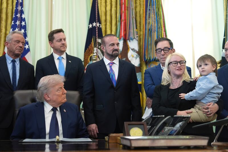 Sierra Smith holds her son Travis, 2, during an event on health care affordability with President Donald Trump, and others, in the Oval Office at the White House, Thursday, April 23, 2026, in Washington. (AP Photo/Mark Schiefelbein)