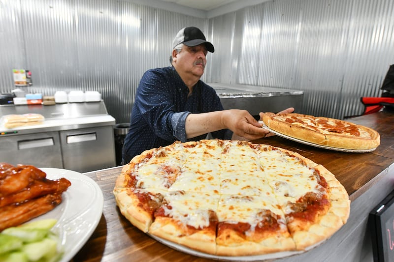 Jose Garfias serves up fresh-made pizzas last week at his restaurant Eva’s Pizza, which he opened with his wife, Eva, in Pembroke Township earlier this month.