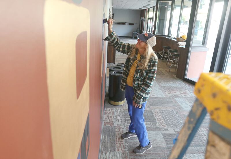 Mary Mauck paints a section of an accent wall in the lobby of the Stage 212 Theater on Wednesday, Oct. 29, 2025 downtown La Salle. The theater's renovation work is wrapping up.