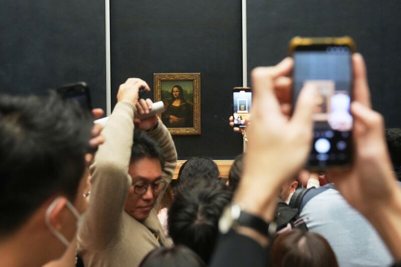 Visitors watch Leonardo da Vinci's painting Mona Lisa in Louvre museum three days after historic jewels were stolen in a daring daylight heist, Wednesday, Oct. 22, 2025 in Paris. (AP Photo/Thibault Camus)