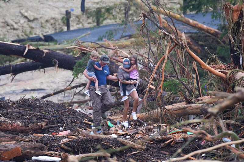 People climb over debris on a bridge atop the Guadalupe River after a flash flood swept through the area Saturday, July 5, 2025, in Ingram, Texas. (AP Photo/Julio Cortez)