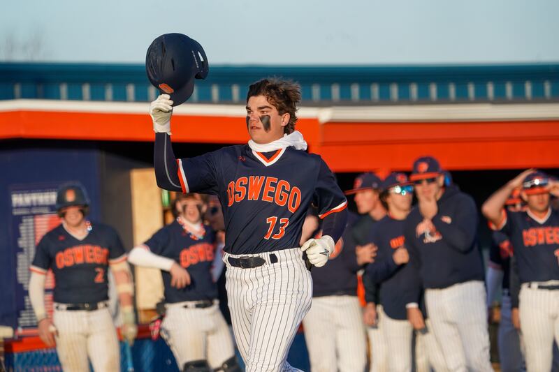 Oswego’s Bryson Norwood (13) tips his helmet as he makes his way to home after hitting a grand slam against Benet during a baseball game at Oswego High School on Tuesday, March 25, 2025.