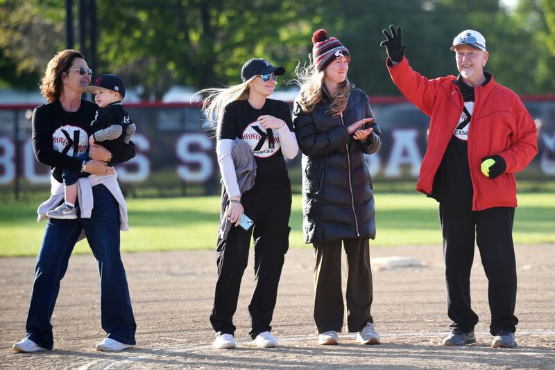 Keith Schweigert, right, waves to the crowd that cheers him on after throwing out a cermonial first pitch ahead of Bradley-Bourbonnais and Bishop McNamara's Strike Out Cancer Night at their softball game in Bourbonnais Thursday, May 8, 2025. From left, are Schweigert's wife Laurie, grandson Noah, daughter-in-law Tami and daughter Kinzie.