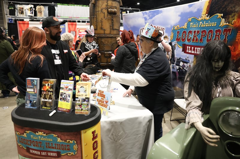 Jessie Wakefield, right, hands out an information pamphlet on upcoming events in Lockport from their booth at C2E2, one of the nations largest comic and entertainment conventions, on Saturday, March 28, 2026 in Chicago.