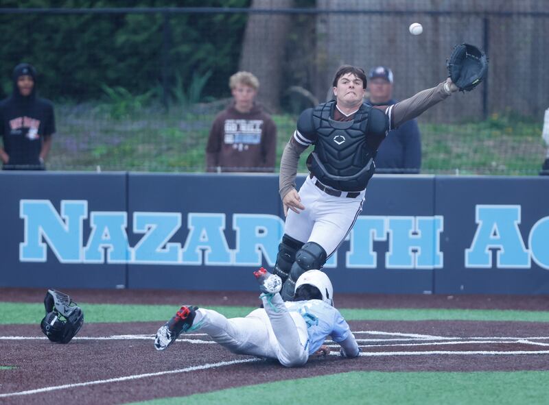 Nazareth's Jaden Fauske (21) slides into home to score the winning run as Joliet Catholic's Zachary Pomatto (34) goes for the ball during the varsity baseball game on Wednesday, April 20, 2025 between Nazareth and Joliet Catholic academies in La Grange Park.
