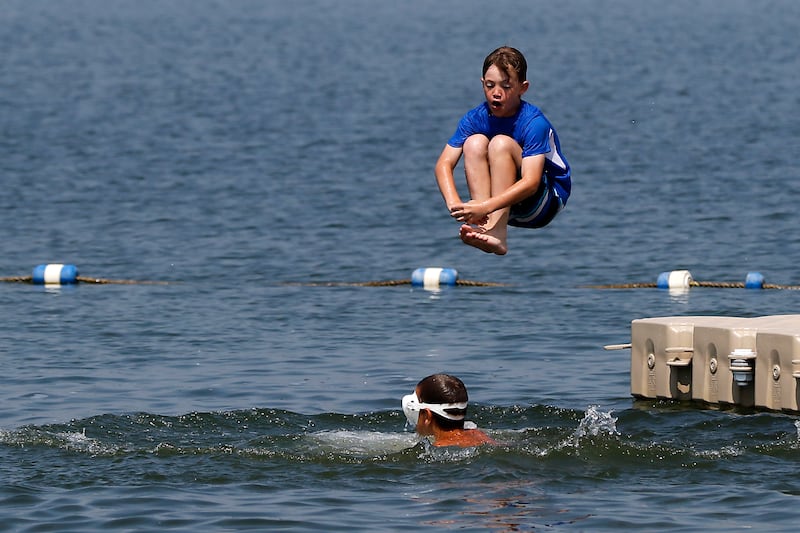 A boy does a cannon ball while swimming at Crystal Lake's Main Beach on Friday, June 21, 2024.