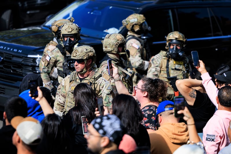 Government officials watch protesters gather in Chicago, Tuesday, Oct. 14, 2025. (Anthony Vazquez/Chicago Sun-Times via AP)