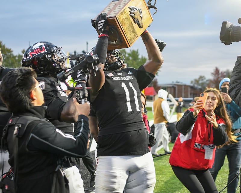 Northern Illinois University's defensive end Jalonnie Williams (11) hoists the trophy up after taking the win over Ball State on Saturday Oct. 25, 2025, held at Huskie Stadium in DeKalb.